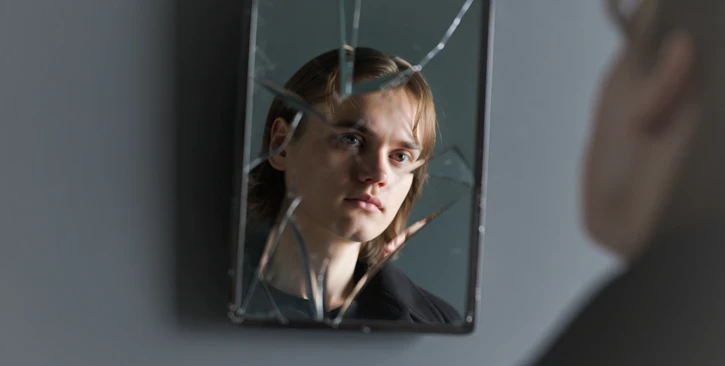 Мужчина смотрится в разбитое зеркало